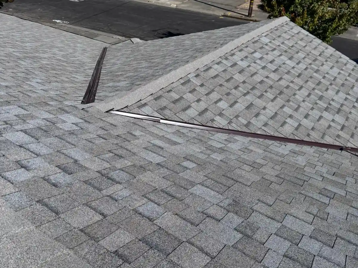 Close-up of an asphalt shingle roof ridge cap and flashing, showing the wear patterns homeowners should watch for in Marin's coastal climate.