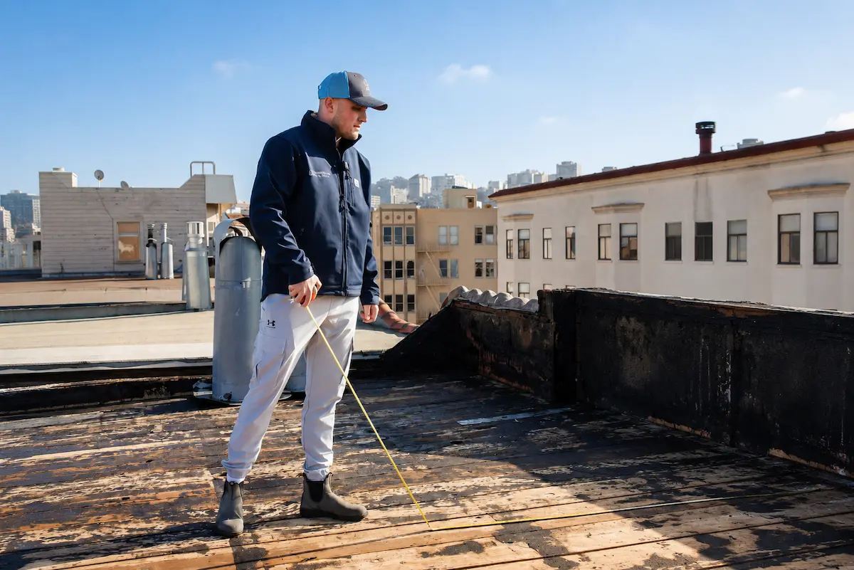 Marina Bay Roofing technician measuring a damaged roof deck during an on-site inspection.
