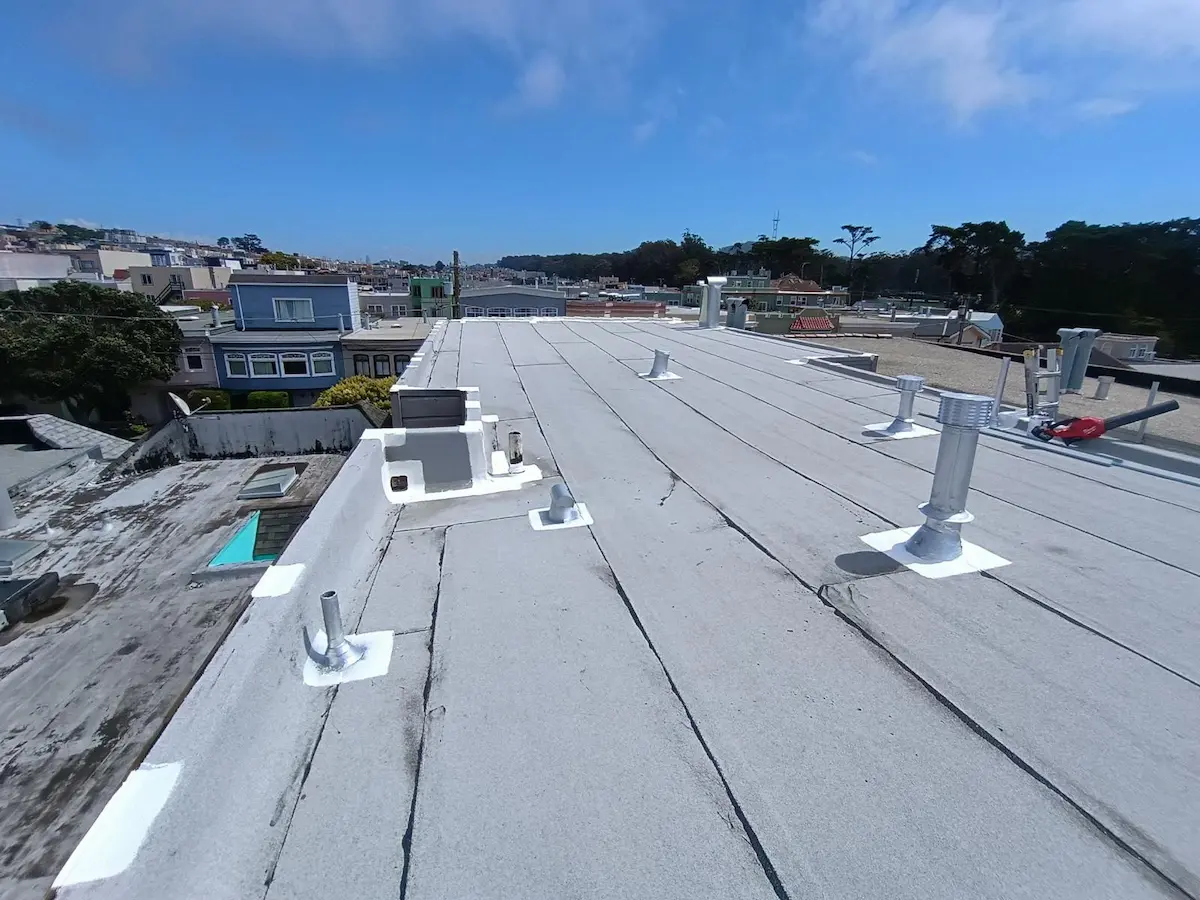 Completed flat roof membrane installation with properly flashed vent penetrations on a residential building.