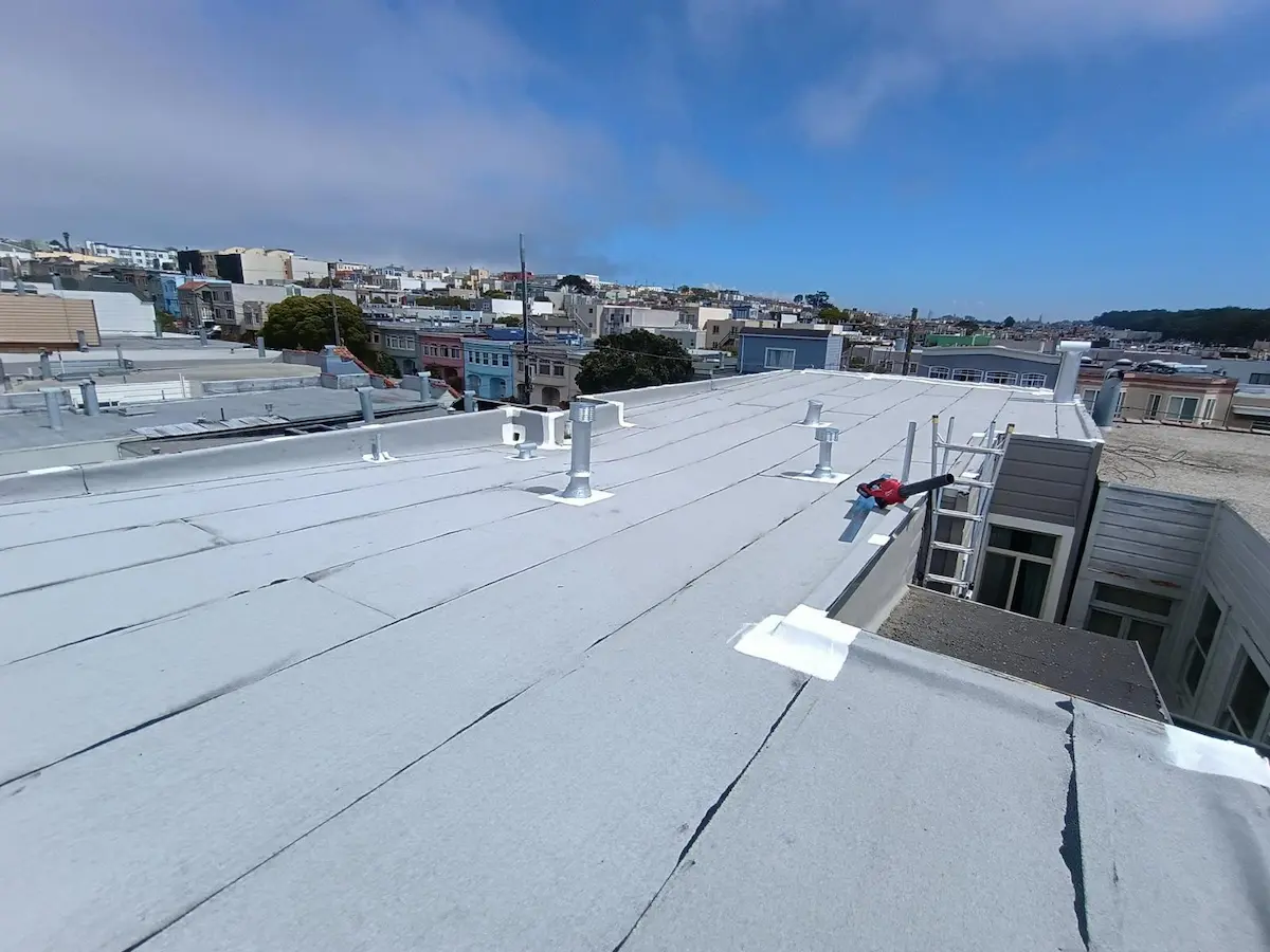 Aerial view of a newly installed TPO flat roof membrane on a San Francisco building with city skyline in the background.